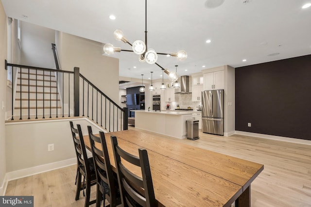 dining area with recessed lighting, baseboards, light wood-style floors, and stairs