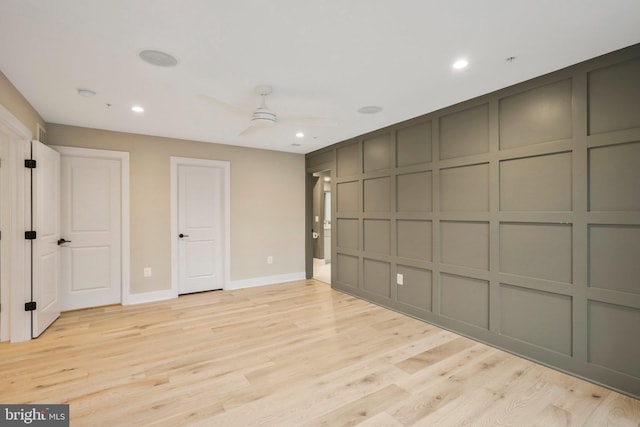 unfurnished bedroom with a ceiling fan, baseboards, recessed lighting, light wood-style floors, and a decorative wall