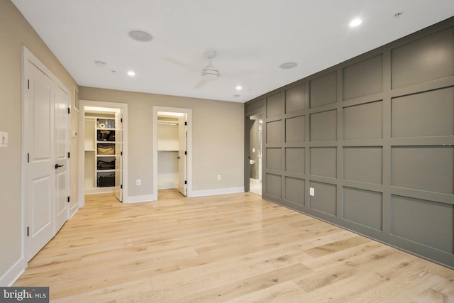 unfurnished bedroom with a decorative wall, recessed lighting, baseboards, and light wood finished floors