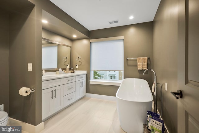 full bath with visible vents, baseboards, double vanity, a soaking tub, and a sink