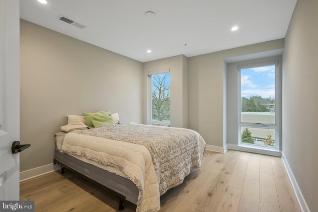 bedroom featuring visible vents, multiple windows, and light wood-style floors