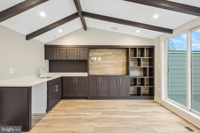 kitchen featuring lofted ceiling with beams, light wood-style floors, and a sink