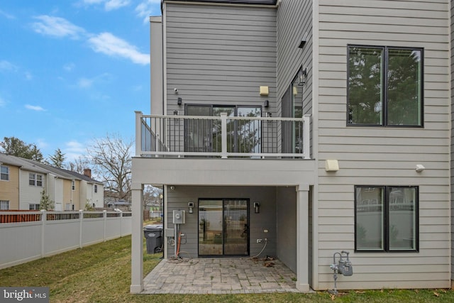 rear view of house featuring a patio, a balcony, and fence