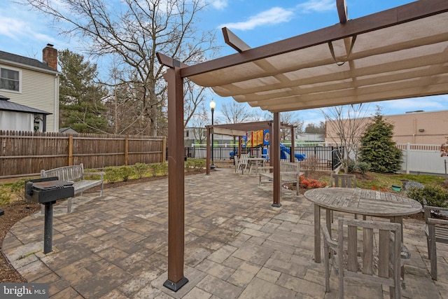 view of patio / terrace with outdoor dining space, a playground, a fenced backyard, and a pergola