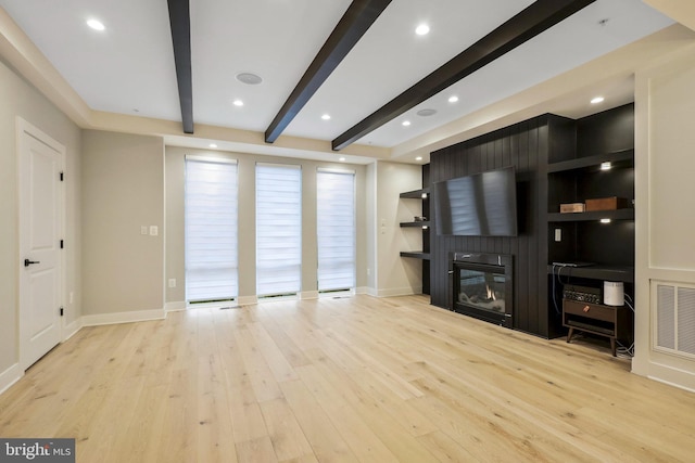 living area featuring visible vents, baseboards, light wood-style flooring, a fireplace, and beamed ceiling