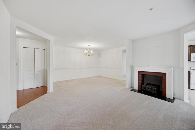 living room with an inviting chandelier, a brick fireplace, and carpet