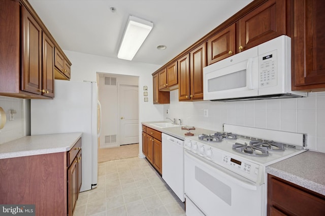 kitchen with visible vents, white appliances, light countertops, and a sink