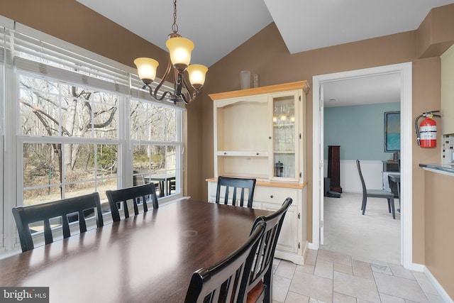 dining space featuring lofted ceiling, baseboards, and a chandelier