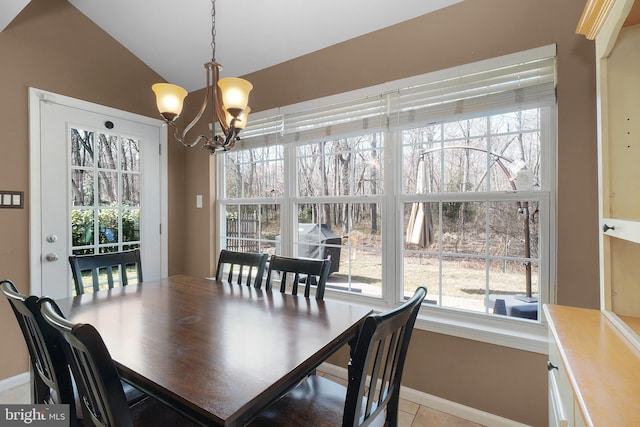 dining space with light tile patterned floors, baseboards, lofted ceiling, and a chandelier