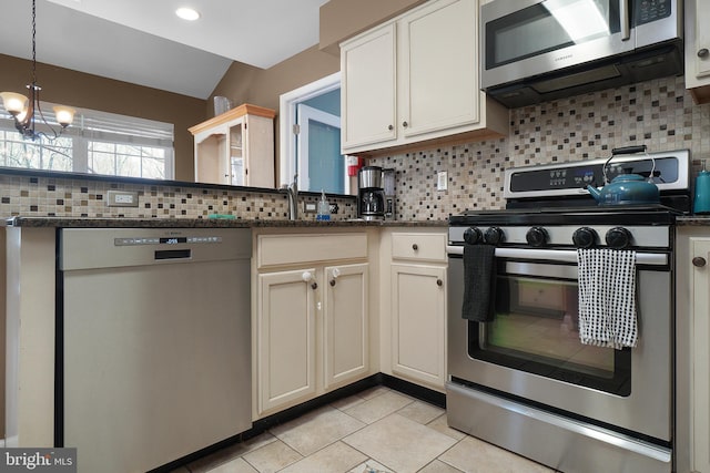 kitchen featuring dark stone countertops, appliances with stainless steel finishes, pendant lighting, a notable chandelier, and tasteful backsplash