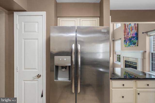 kitchen with dark countertops, plenty of natural light, stainless steel fridge, and a high end fireplace