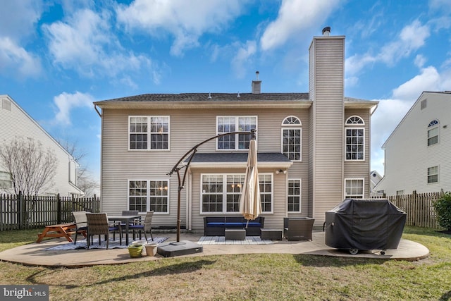 rear view of house featuring outdoor lounge area, a patio area, a fenced backyard, and a chimney