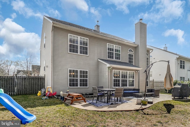 rear view of property featuring a playground, a patio area, fence, and a lawn