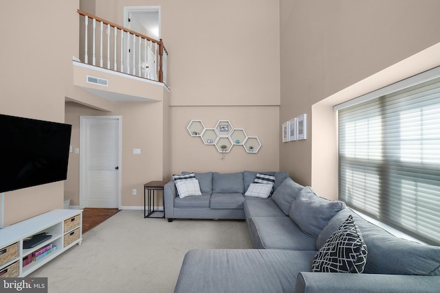 living room featuring visible vents, carpet flooring, baseboards, and a towering ceiling