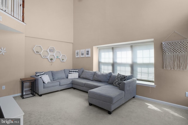 carpeted living room with a healthy amount of sunlight, baseboards, and a towering ceiling