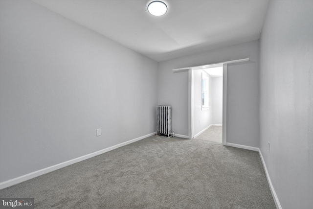 carpeted spare room featuring radiator heating unit and baseboards