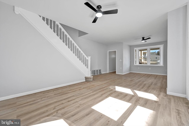 unfurnished living room featuring visible vents, a ceiling fan, wood finished floors, baseboards, and stairs