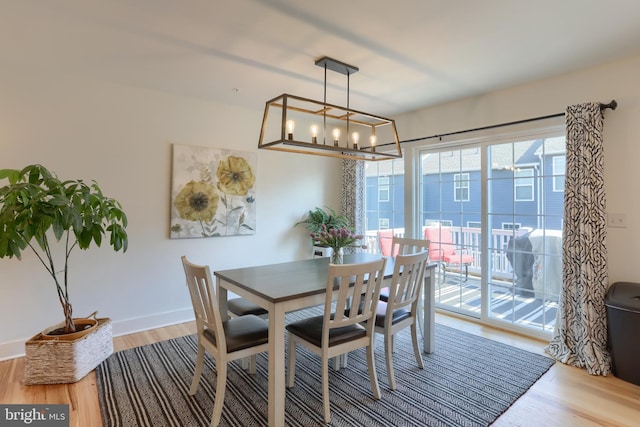 dining area with baseboards, an inviting chandelier, and wood finished floors