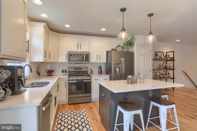 kitchen with white cabinets, appliances with stainless steel finishes, a kitchen bar, and a sink