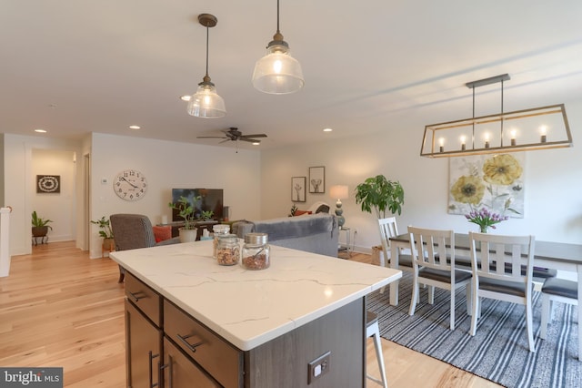 kitchen with ceiling fan, open floor plan, a breakfast bar, recessed lighting, and light wood-style floors