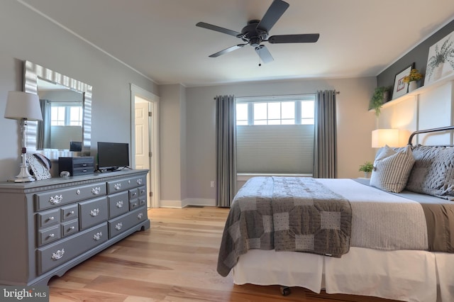 bedroom featuring baseboards, light wood-style floors, and a ceiling fan