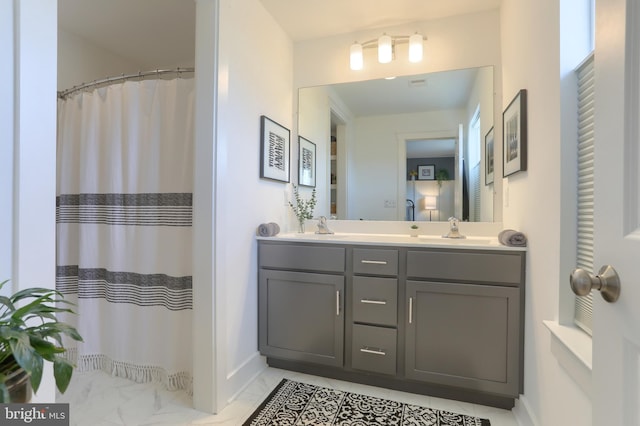 full bathroom with double vanity, marble finish floor, baseboards, and a sink