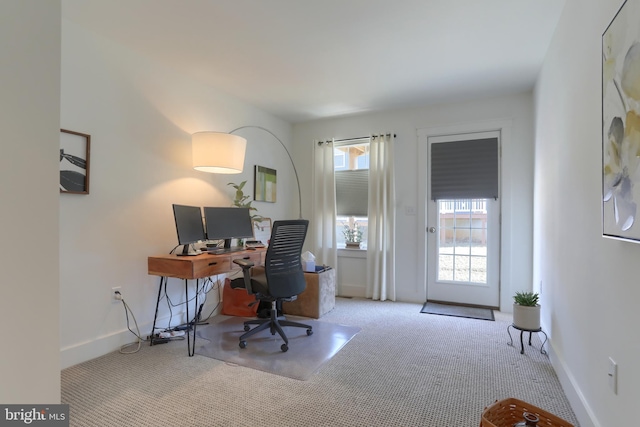 carpeted office space featuring plenty of natural light and baseboards