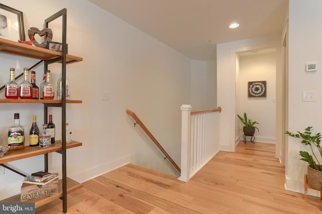 corridor with light wood-style flooring, recessed lighting, an upstairs landing, and baseboards