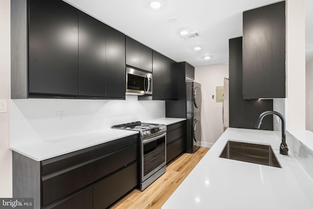 kitchen with dark cabinetry, visible vents, a sink, light countertops, and appliances with stainless steel finishes