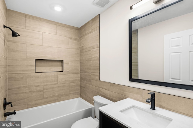 bathroom with visible vents, toilet, tile walls, tub / shower combination, and vanity