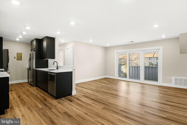 kitchen with freestanding refrigerator, dishwasher, light countertops, and dark cabinetry