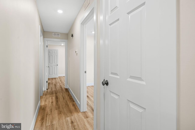 corridor featuring light wood finished floors, visible vents, and baseboards