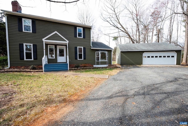 colonial inspired home featuring an outbuilding, a chimney, and a detached garage