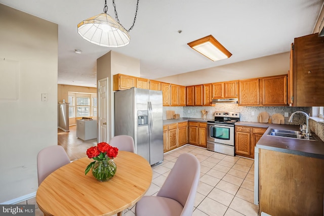 kitchen featuring under cabinet range hood, stainless steel appliances, tasteful backsplash, and a sink