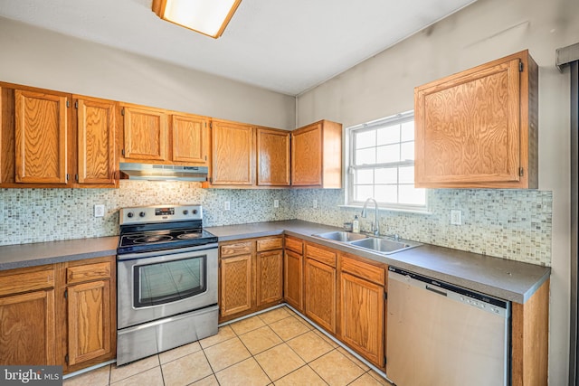 kitchen with tasteful backsplash, under cabinet range hood, light tile patterned floors, appliances with stainless steel finishes, and a sink