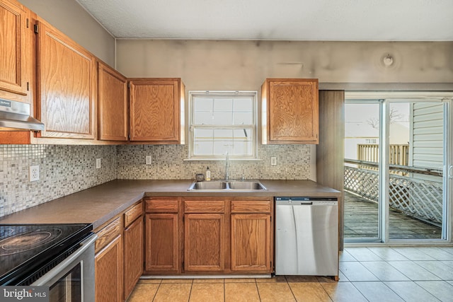 kitchen featuring a sink, dark countertops, backsplash, appliances with stainless steel finishes, and light tile patterned floors