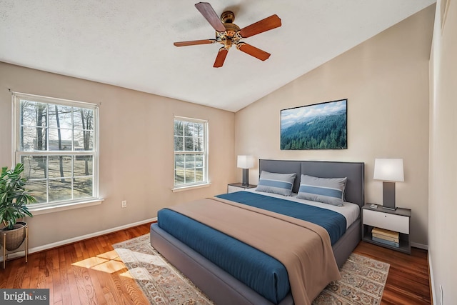 bedroom with baseboards, multiple windows, wood finished floors, and vaulted ceiling