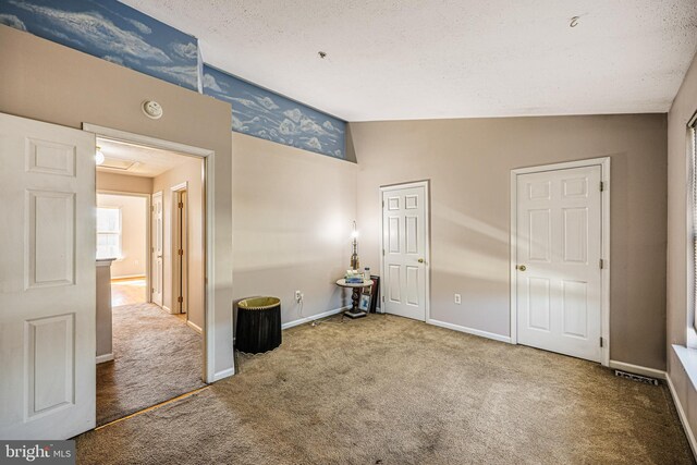 unfurnished bedroom with vaulted ceiling, baseboards, carpet floors, and a textured ceiling