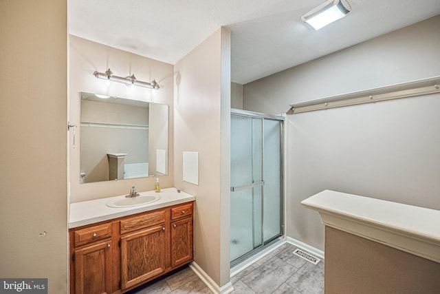 full bathroom featuring visible vents, baseboards, vanity, and a shower stall