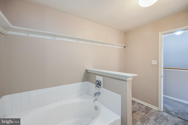 full bath with baseboards, a textured ceiling, and a garden tub