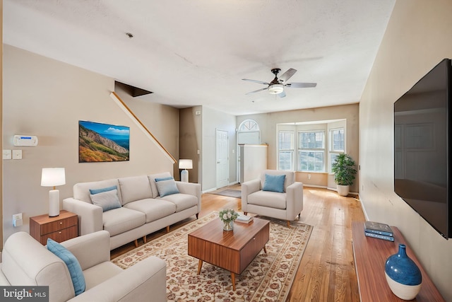 living room with baseboards, light wood-type flooring, and a ceiling fan