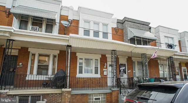 view of property featuring a porch and brick siding