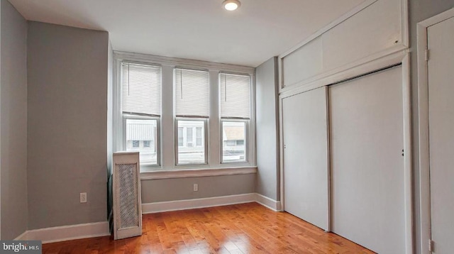 unfurnished bedroom with a closet, baseboards, and light wood-style flooring