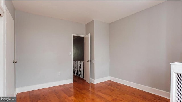 unfurnished room with baseboards and wood finished floors