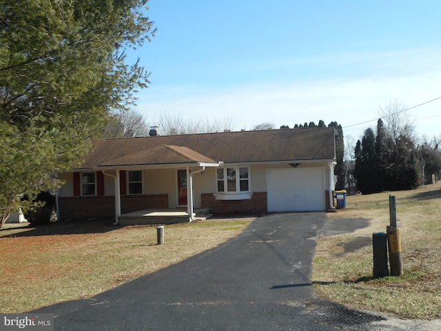 single story home with a front lawn, driveway, a porch, a garage, and brick siding