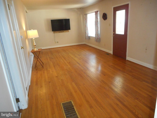 unfurnished living room with visible vents, baseboards, and hardwood / wood-style flooring