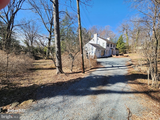 view of property exterior featuring driveway and a chimney