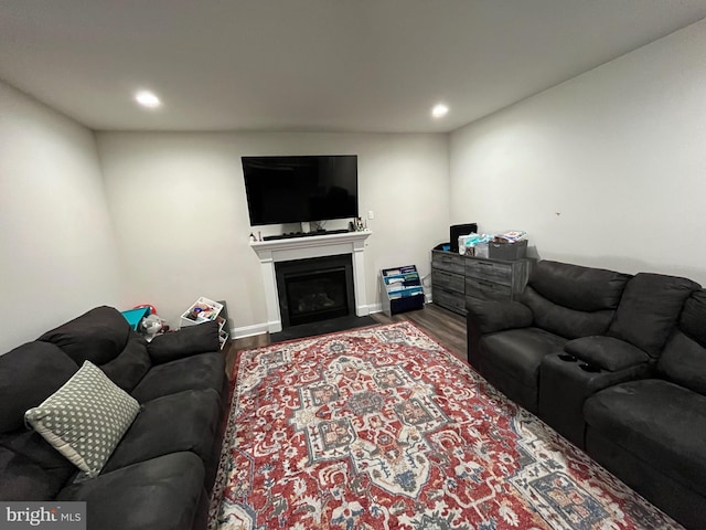 living area featuring recessed lighting, a fireplace with flush hearth, and wood finished floors