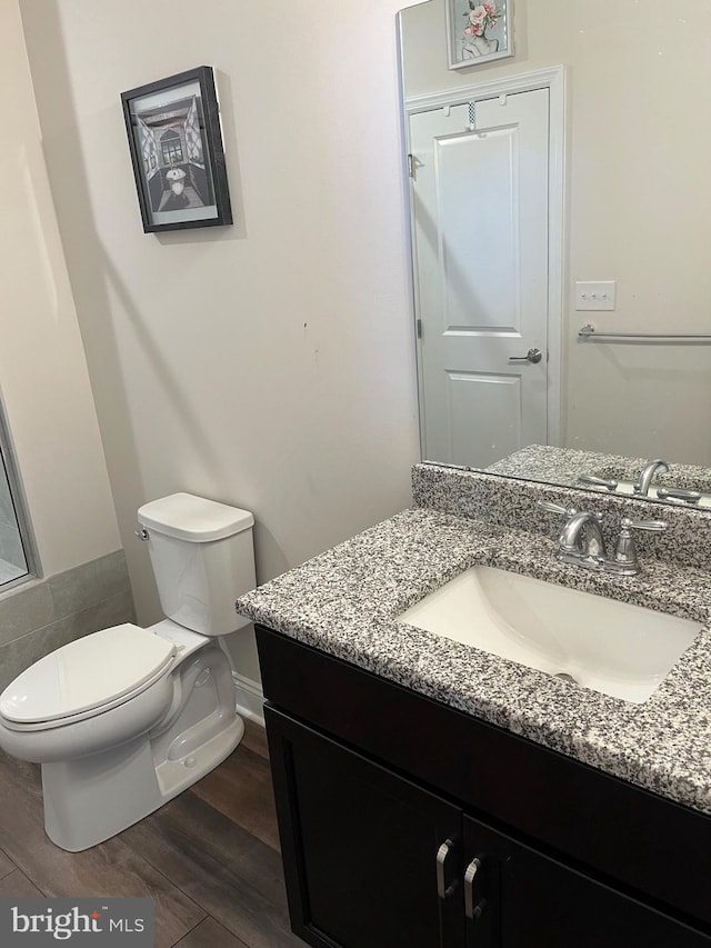 bathroom with toilet, wood finished floors, and vanity