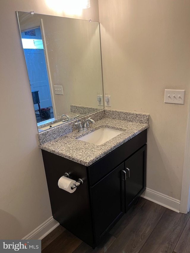 bathroom with vanity, baseboards, and wood finished floors